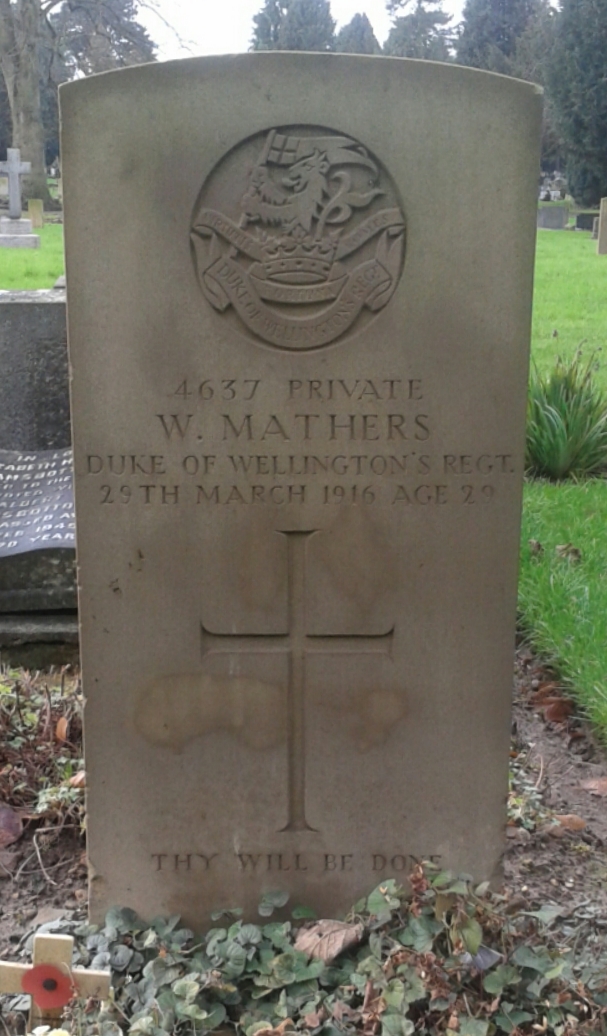 A war grave headstone in a graveyard with ivy on the ground.
