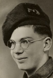 A close up photographic portrait of a young man wearing Army uniform. He has a scottish cap with the badge of the Gordon Highlanders.