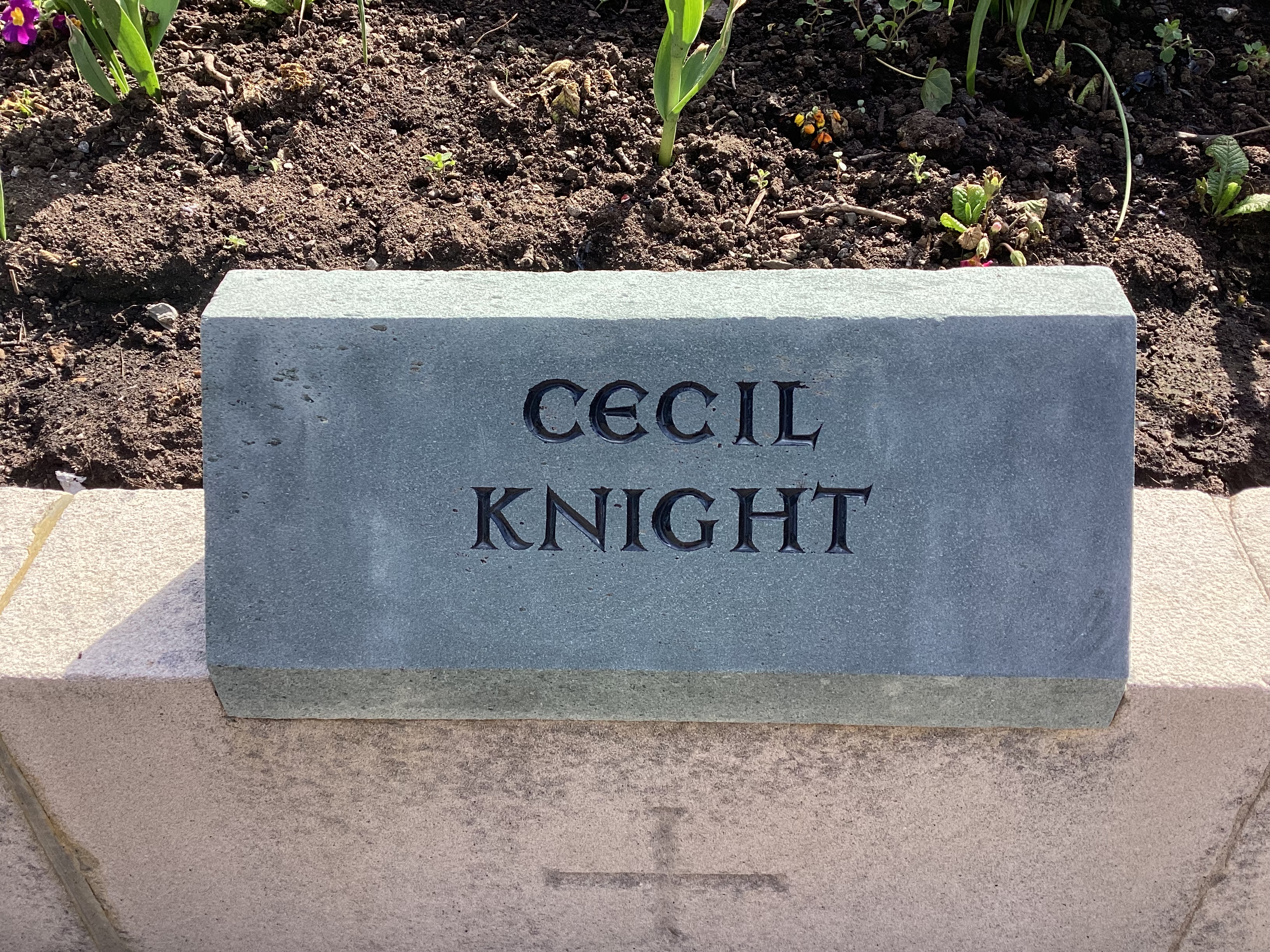 A green slate memorial stone with the name CECIL KNIGHT engraved in black lettering.