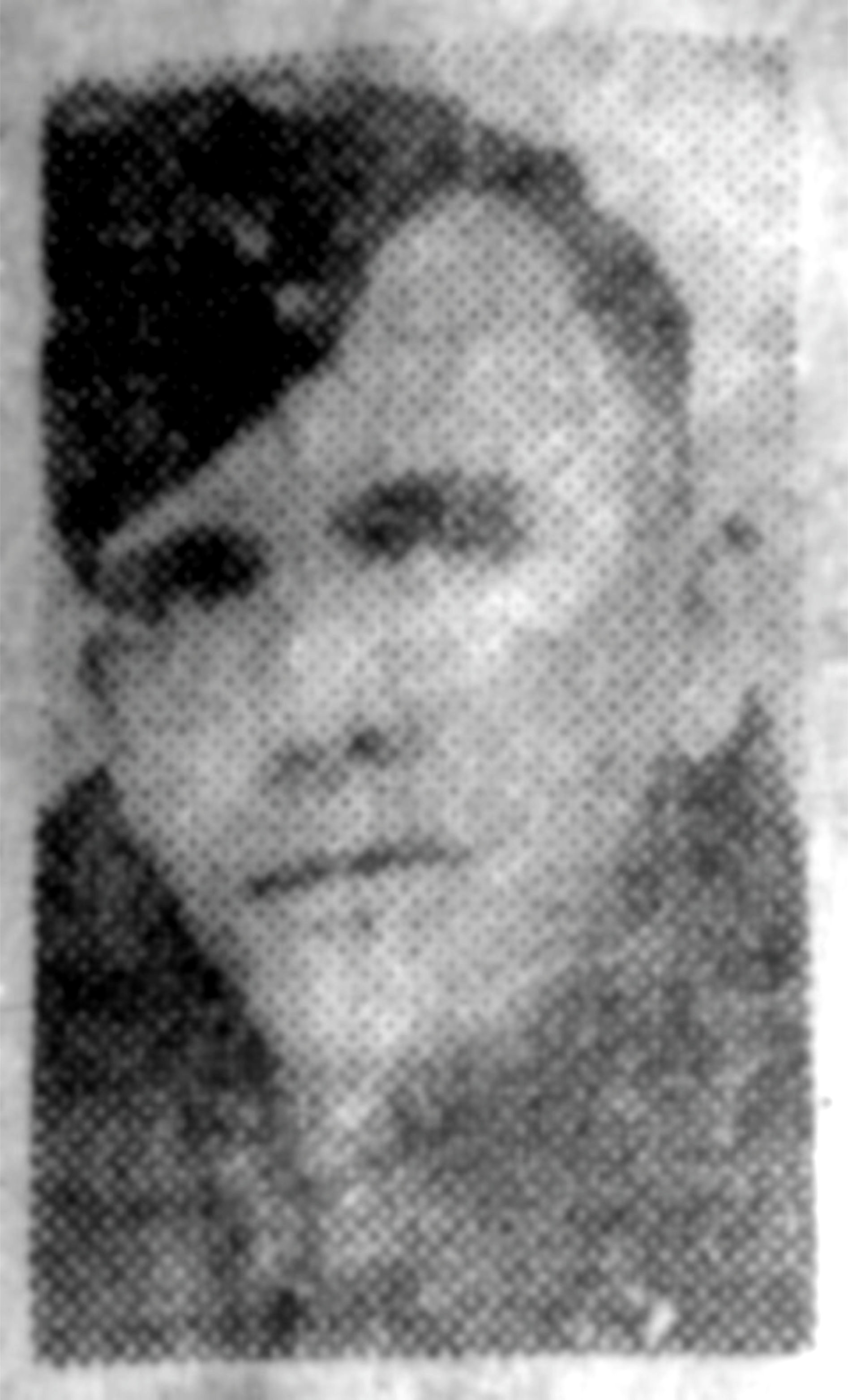 A very grainy newspaper ohotograph of a soldier wearing a forage cap and a coat with the collar up.