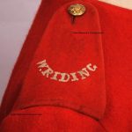 A scarlet frock epaulette with the letters: W.RIDING embroidered in white thread.