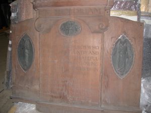 A light brown Oak war memorial with three oval bronze panels. The names of the fallen are engraved in a central pane.