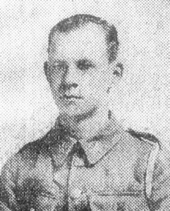 An old newspaper portrait photo of a soldier. He is wearing an army jacket but has no cap and is facing the camera..