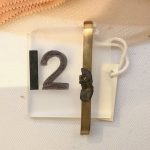 A brass tiepin with a tiny piece of metal shrapnel mounted on the front.