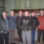 Six men who removed the memorial from the wall. The memorial is behind them leaned against the wall.