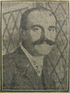 A poor quality image from a newspaper over 100 years old. It is a head and shoulders view of a bald-headed man facing the camera. He has a large bushy moustache.