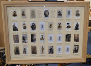A framed and glazed war memorial with thirty photographs spaced apart with a special mount and calligrahy titles.