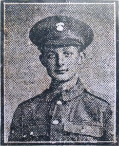 A newspaper image of a man's head and shoulders. He is wearing Army uniform and a peaked cap with a badge.