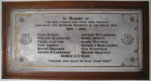 A white marble plaque mounted on a wooden board. The lettering is engraved and detailed in black paint with a gold paint border.
