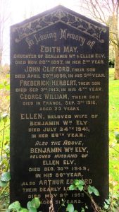 A black granite headstone with gold lettering, situated in a local cemetery.