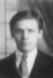 An out of focus photograph of a young man wearing a suit jacket, white shirt and tie.
