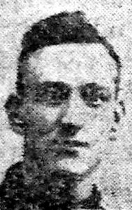 A rather poor quality photograph from a 1918 newspaper. It is of a man's head and shoulders and he is facing the camera.