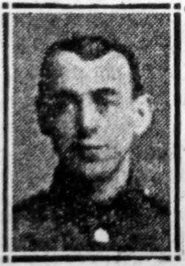 A rather poor quality photograph from a 1918 newspaper. It is of a man's head and shoulders and he is facing the camera.