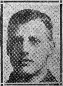 A rather poor quality photograph from a 1918 newspaper. It is of a man's head and shoulders and he is facing the camera.