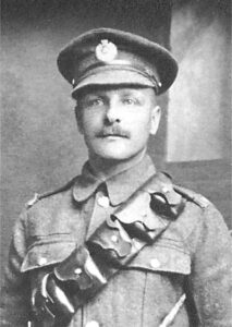 A photograph of a Royal Engineers soldier in a studio. He is wearing a peaked cap with the regimental badge and facing the camera.