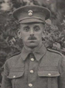 A photograph of a Northumberland Fusiliers soldier in a studio. he is wearing a peaked cap with the regimental badge and facing the camera.